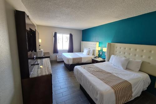 a hotel room with two beds and a blue wall at Rodeway Inn in Bloomington