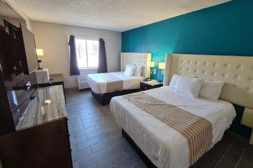 a hotel room with two beds and a blue wall at Rodeway Inn in Bloomington