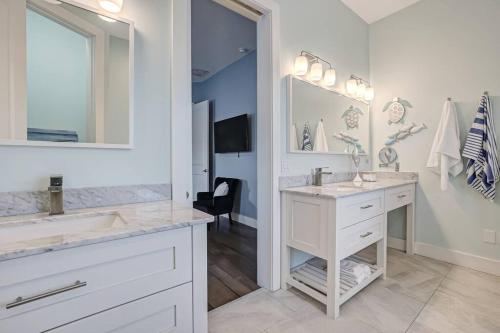 a white bathroom with two sinks and a mirror at Sunkissed Sands in St. Augustine