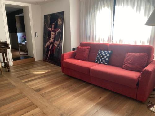 a red couch in a living room with wood floors at Luxury apartment (Porta Venezia) in Milan