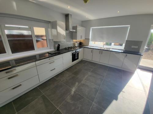 a large kitchen with white cabinets and a large window at High Spec Large 6 Bedroom House! in Kingston upon Thames