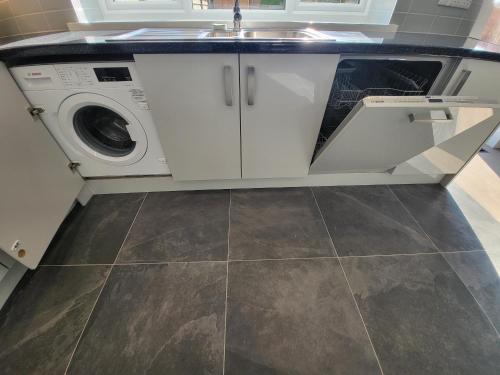 a kitchen with a sink and a washing machine at High Spec Large 6 Bedroom House! in Kingston upon Thames