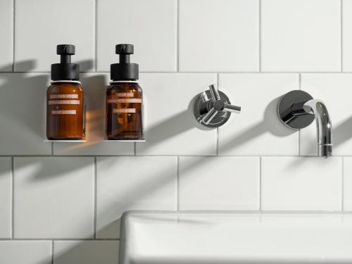 two bottles of soap on a shelf above a sink at Townhouse Maastricht & Spa in Maastricht