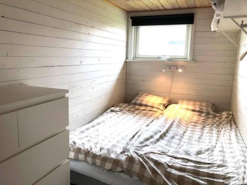 a small bed in a room with a window at Havsnära arkitektritad stuga i Ölmanäs, Gårda brygga in Åsa