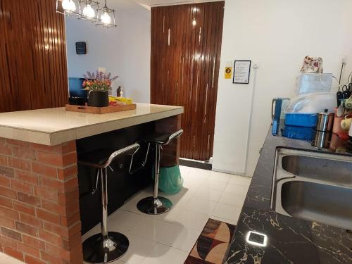 a kitchen with a counter with two stools next to a sink at Islamic Homestay Apartment Kundang, Rawang in Rawang