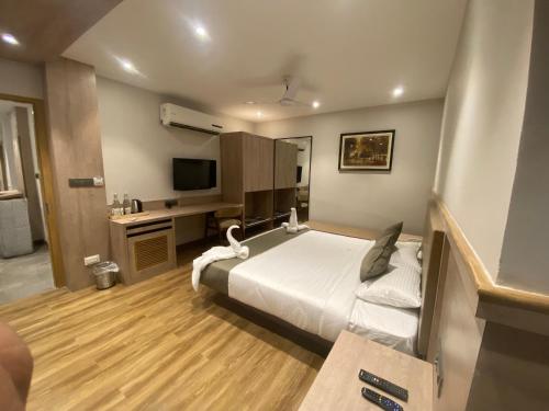 PānchuriaにあるFirangipani Suites - A Corporate Boutique Hotelのベッドとテレビが備わるホテルルームです。
