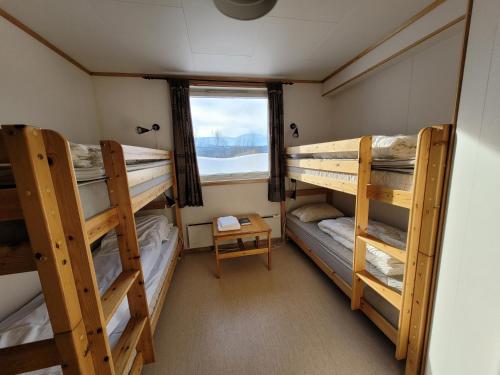a room with three bunk beds and a window at Soltun Soldatheim & Ungdomssenter in Sætermoen