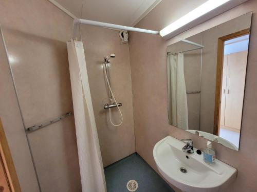 uma casa de banho com um lavatório e um chuveiro com um espelho. em Soltun Soldatheim & Ungdomssenter em Sætermoen