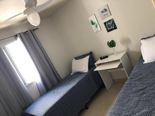 a bedroom with two beds and a desk and a window at A Passos da Areia Apartamento 2 Quartos no Coração da Badalada Praia do Morro - WiFi Fibra in Guarapari