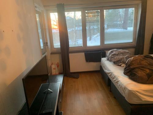 a room with a bed and a table and windows at Very Nice Apartment 15 minutes from Stockholm in Trångsund