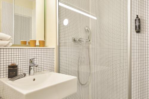 a white bathroom with a sink and a shower at ibis budget Paris Porte d'Aubervilliers in Aubervilliers
