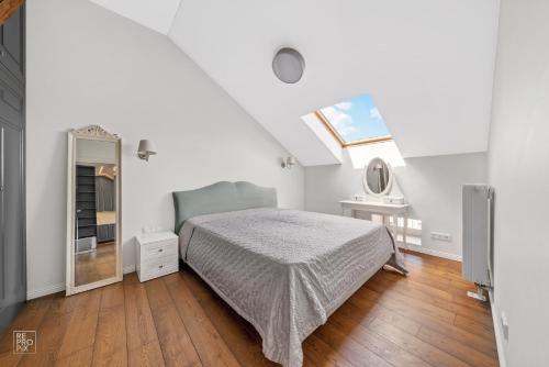 a white bedroom with a bed and a mirror at Cozy Old Town apartment in Kaunas