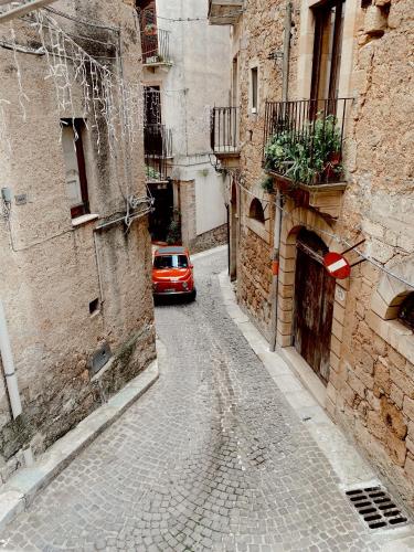 a red car driving down a street in an alley at Don Nicuzzo in Salemi