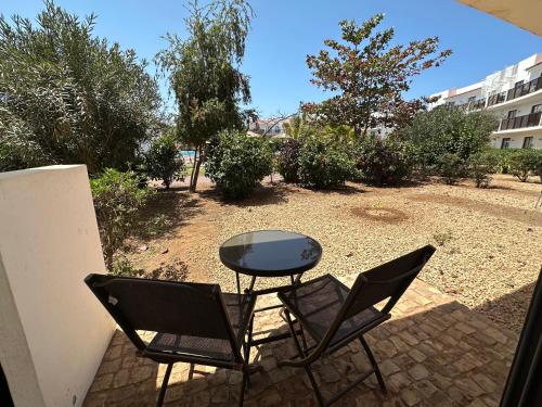 a patio with two chairs and a glass table at Quality Melia Dunas Beach Resort Apt Spa Gym 7 Pools in Santa Maria