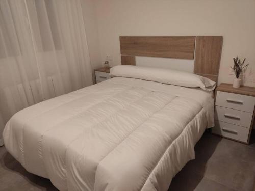 a bedroom with a white bed with a wooden headboard at Casa rural Fuente Americana in Moratalla