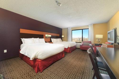 a hotel room with two beds and a flat screen tv at TownePlace Suites Farmington in Farmington