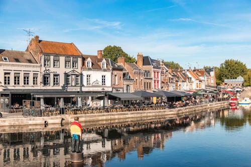 a person with a rainbow umbrella standing next to a river at Le cocon amiénois in Amiens