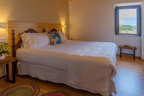 um quarto com uma grande cama branca e uma janela em O Viso Ecovillage - Hotel Ecologico Vegano em Orol