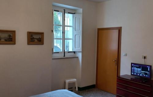 a bedroom with a bed and a window and a television at The Englishmans Home in Cuglieri