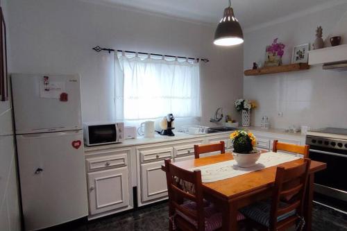 a kitchen with a table and a white refrigerator at Casa Da Torre in Ribeira Grande