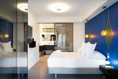 a bedroom with a white bed and a blue wall at Les Suites 7 Anges - Parking, Vue Cathédrale & Centre Historique Reims in Reims