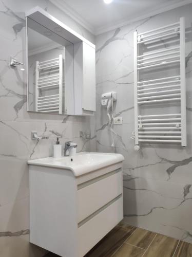 a white bathroom with a sink and a mirror at Eni entire guesthouse parking on site in Berat