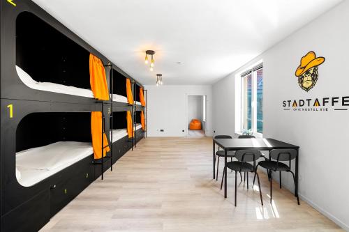 Cette chambre comprend des lits superposés, une table et des chaises. dans l'établissement Stadtaffe - Chic Hostel VIE, à Vienne