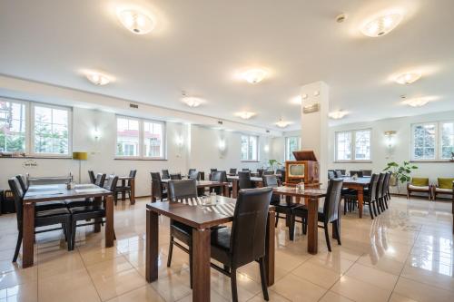 a dining room with tables and chairs and windows at Villa Tilia in Polanica-Zdrój