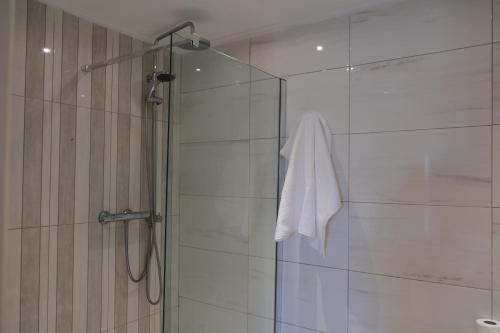 ducha con puerta de cristal y toalla blanca en Penthouse with sea view, lift, 2 min from Valletta, en Floriana