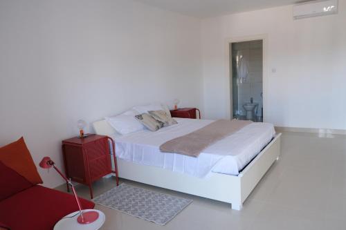 1 dormitorio blanco con 1 cama y 1 silla roja en Penthouse with sea view, lift, 2 min from Valletta, en Floriana