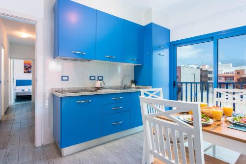 eine Küche mit blauen Schränken und einem Esstisch in der Unterkunft Riva Eco Guest House in Los Abrigos