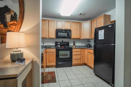 a kitchen with a black refrigerator and wooden cabinets at MVC - Unit 1405 - Bears Lair in Pigeon Forge
