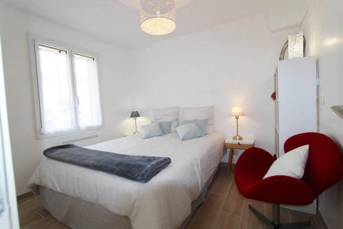 a white bedroom with a large bed and a red chair at Cocon à la campagne - Disney 20 min - Paris 40 min - 2 terrasses in Dammartin-sur-Tigeaux