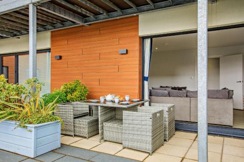 un patio con una mesa y sillas de mimbre en 2 Challacombe - Luxury Apartment at Byron Woolacombe, only 4 minute walk to Woolacombe Beach!, en Woolacombe