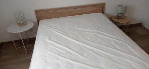 a bed with a white sheet on it in a room at ANCELLE TAILLAS RDC CHALET in Ancelle
