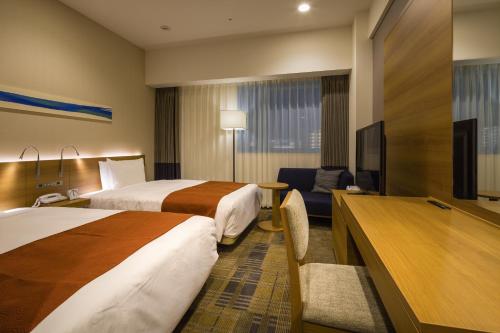a hotel room with two beds and a flat screen tv at Hotel Sunroute Chiba in Chiba