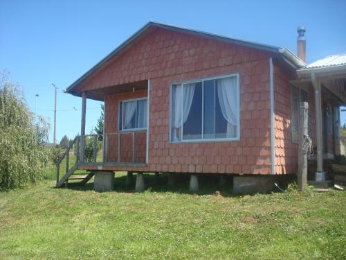 a small red house with a bench in front of it at Cabaña Vista al Lago in Llanquihue