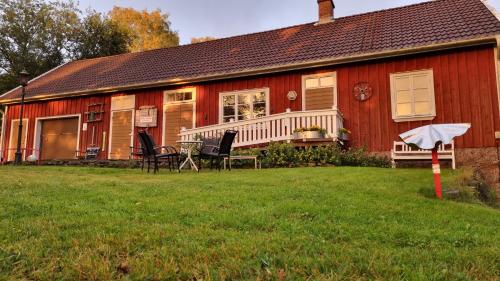 une maison rouge avec des chaises et un parasol devant elle dans l'établissement Fageredsgården, à Ullared