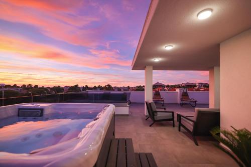 a hot tub on a balcony with a sunset at Leonardo Luxury Residence 2 Penthouse with jacuzzi in Zadar