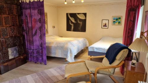 a bedroom with two beds with purple curtains and a chair at Fageredsgården in Ullared