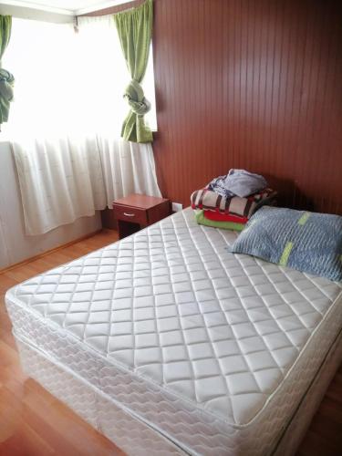 een groot wit bed in een slaapkamer met een raam bij Hospedaje familiar johana in Puerto Montt