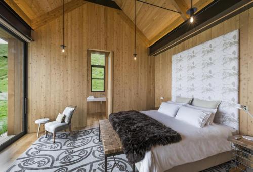 a bedroom with a large bed in a room with wooden walls at Annandale Coastal Farm Escape & Luxury Villa Collection in Akaroa