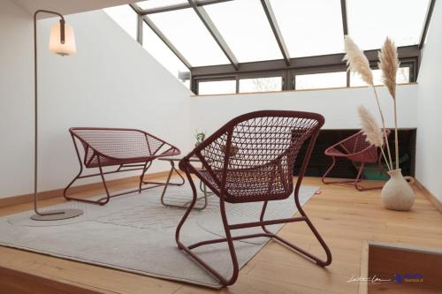 3 Stühle und ein Tisch in einem Zimmer mit Fenstern in der Unterkunft Jardin des Anges - Castillet view - WIFI- Centre ville in Perpignan