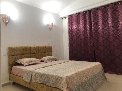 a bedroom with a bed with purple curtains at Dar Slima in Aghīr