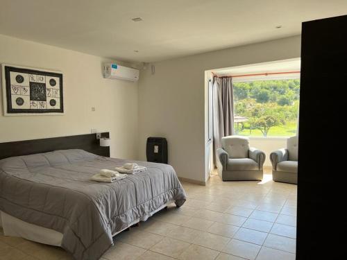 um quarto com uma cama, 2 cadeiras e uma janela em La Herradura Village em Merlo
