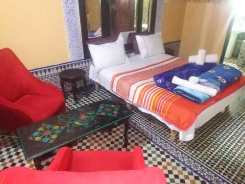 um quarto com uma cama, uma cadeira e uma mesa em riad zahra em Fez