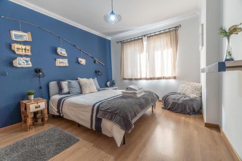 Un dormitorio con una cama y una pared azul. en The Port Beach House, en Praia da Areia Branca