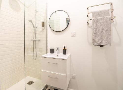 een witte badkamer met een wastafel en een spiegel bij La Vigne Nature T2 au cœur historique de Blaye in Blaye