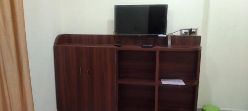 - une télévision installée au-dessus d'un support en bois dans l'établissement New Milan Palace, DEOGHAR, à Deoghar