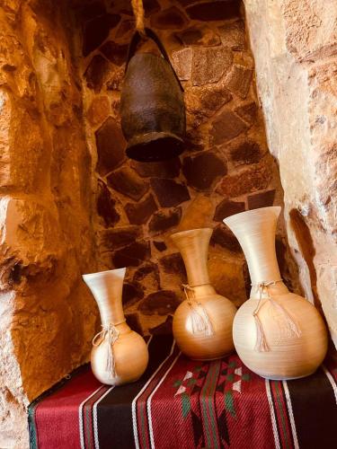 three vases sitting on a table in front of a stone wall at Petra fort hotel in Wadi Musa